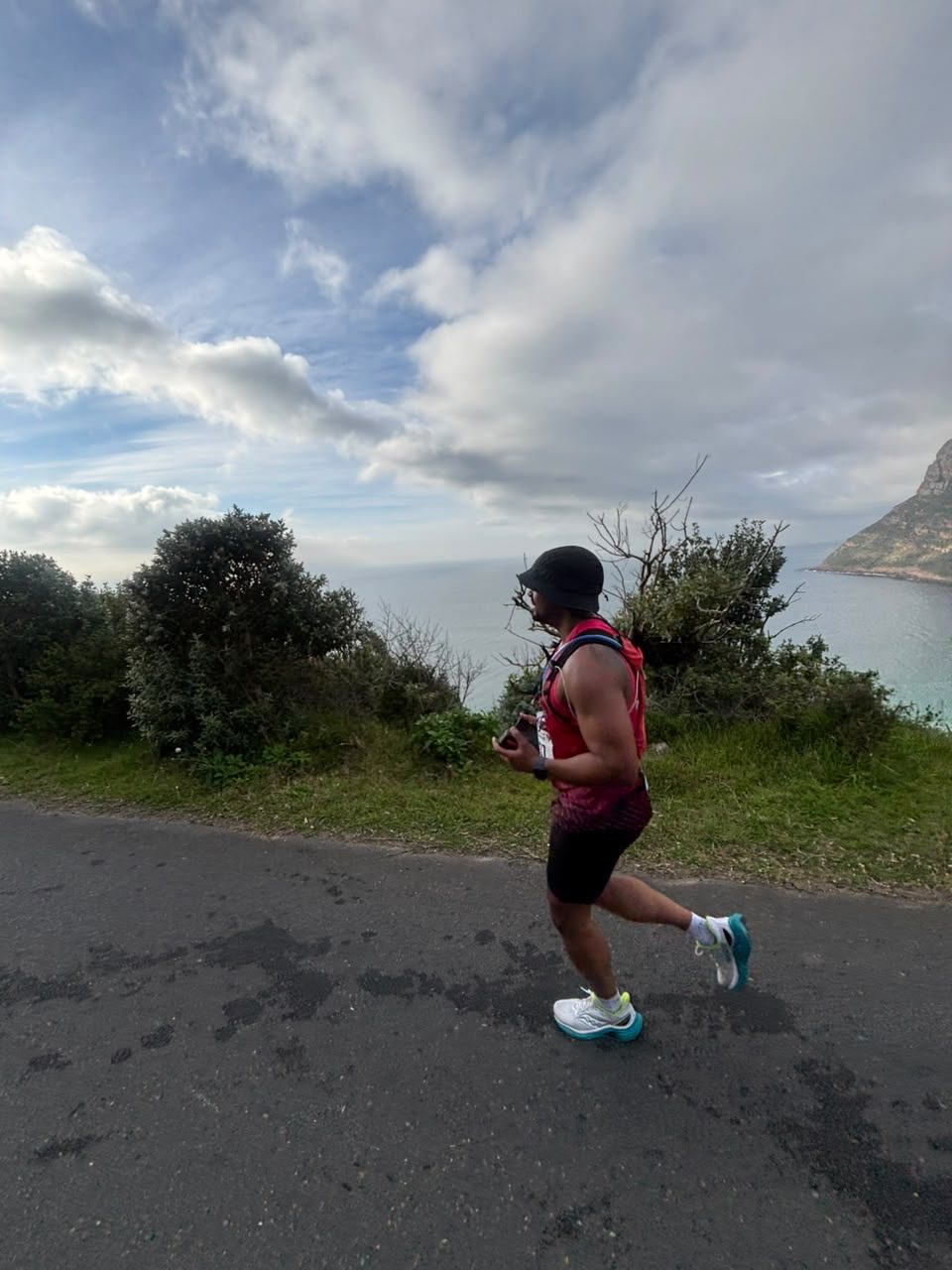 Shaun Cedric Thomas running on a coastal road above the sea in Cape Town